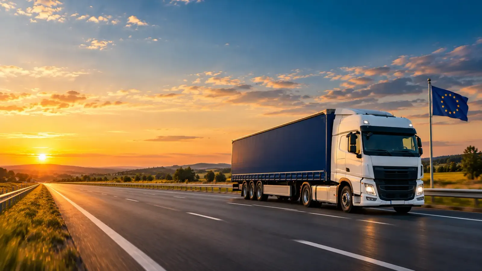 Ciężarówka z granatową naczepą na autostradzie o zachodzie słońca, obok flaga Unii Europejskiej